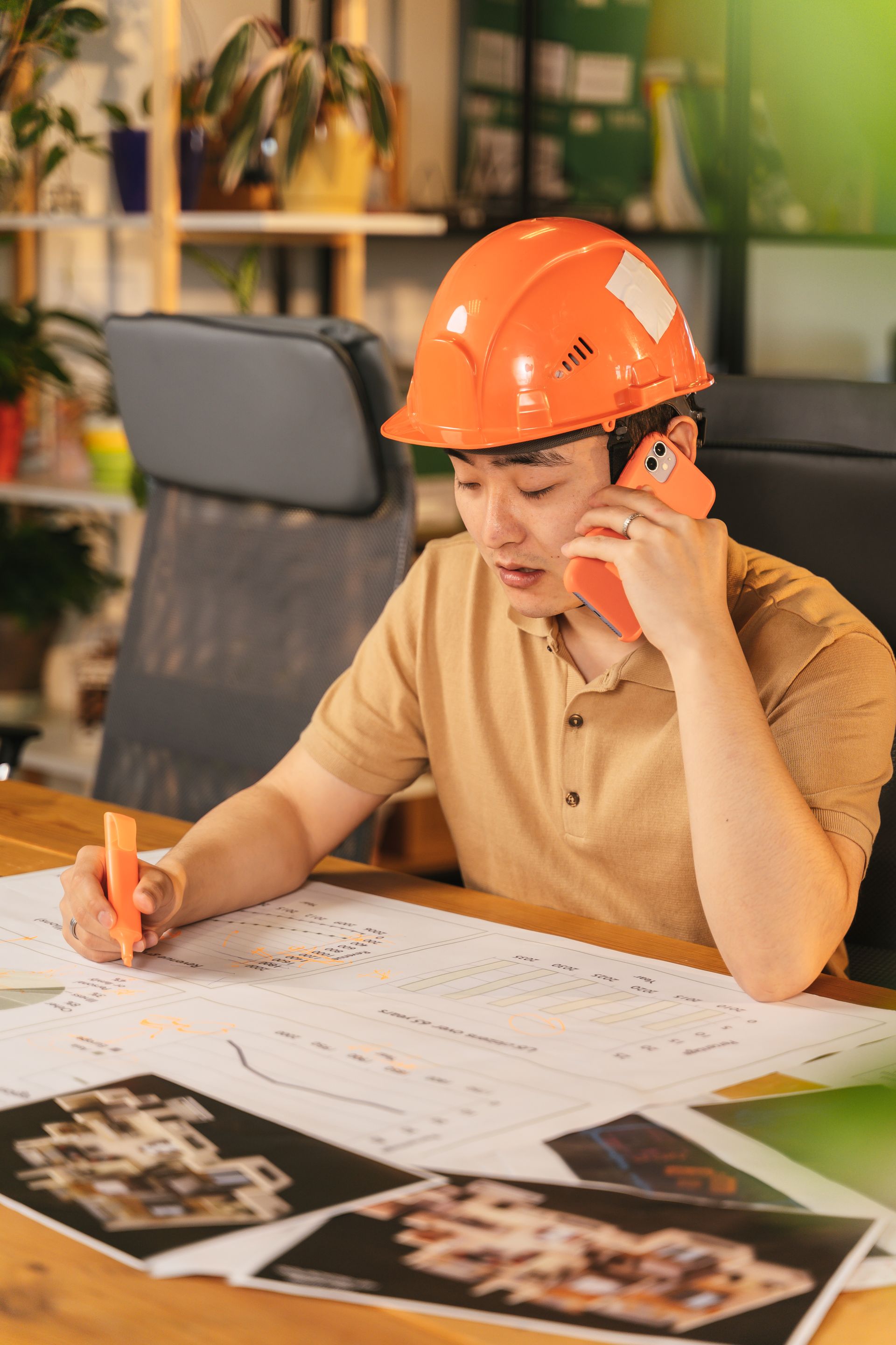 Tradesman in a hard hat reviewing plans while taking a call
