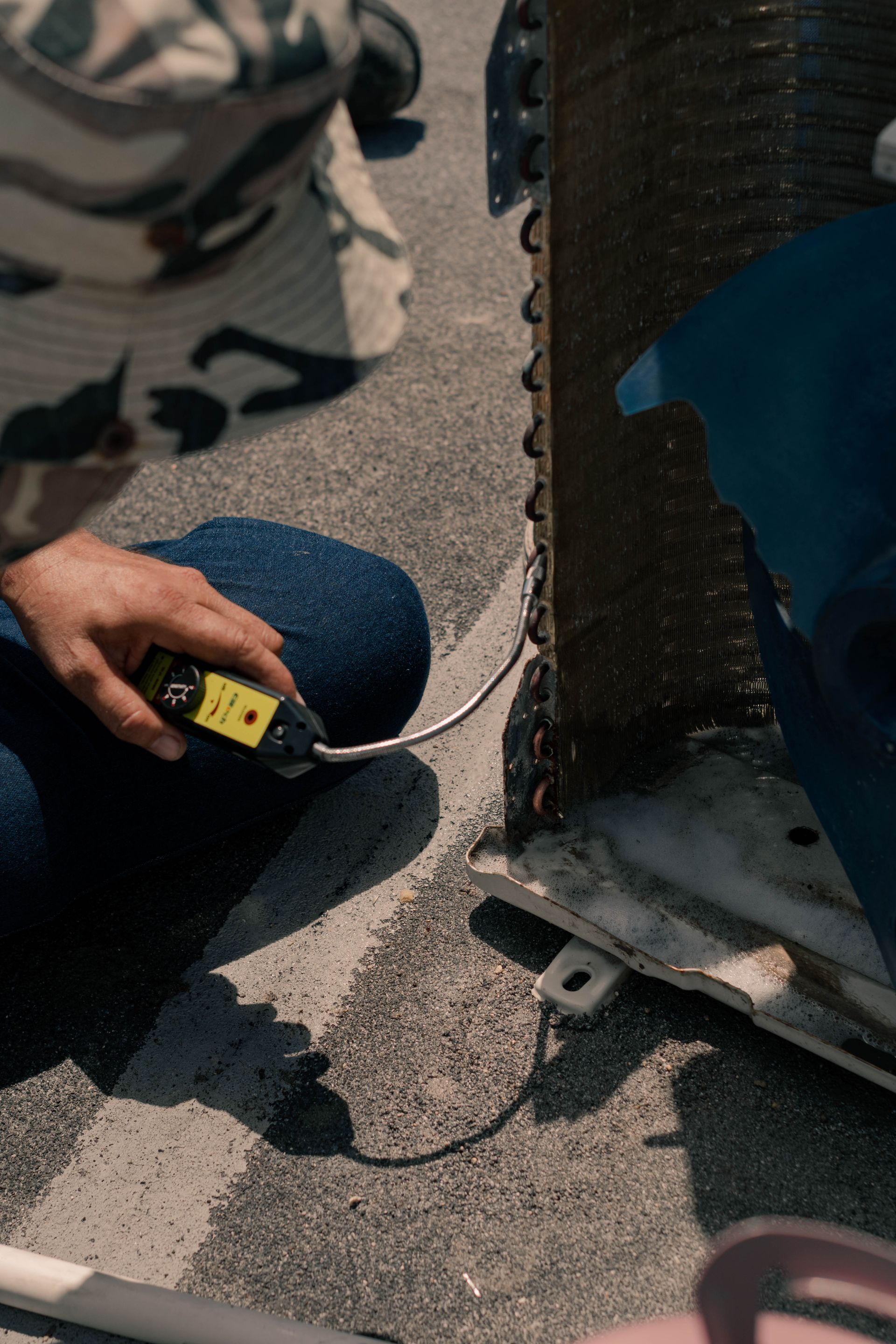 Technician testing an air conditioning condenser coil