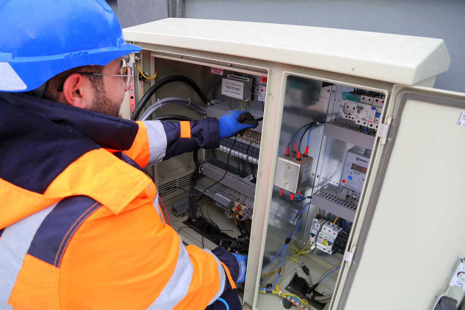 Electrician in high-vis working on a switchboard