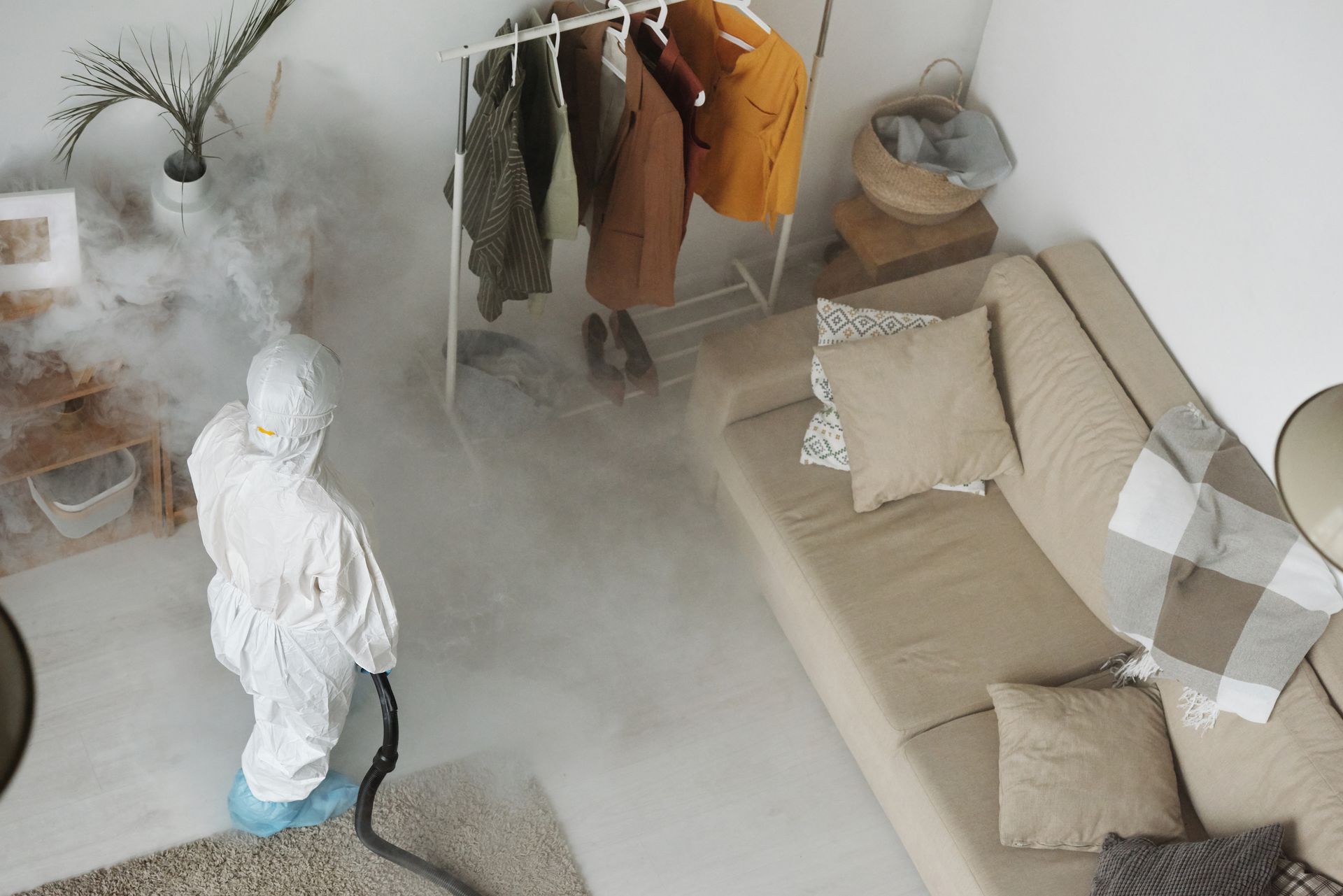 Pest technician in protective gear treating a living room