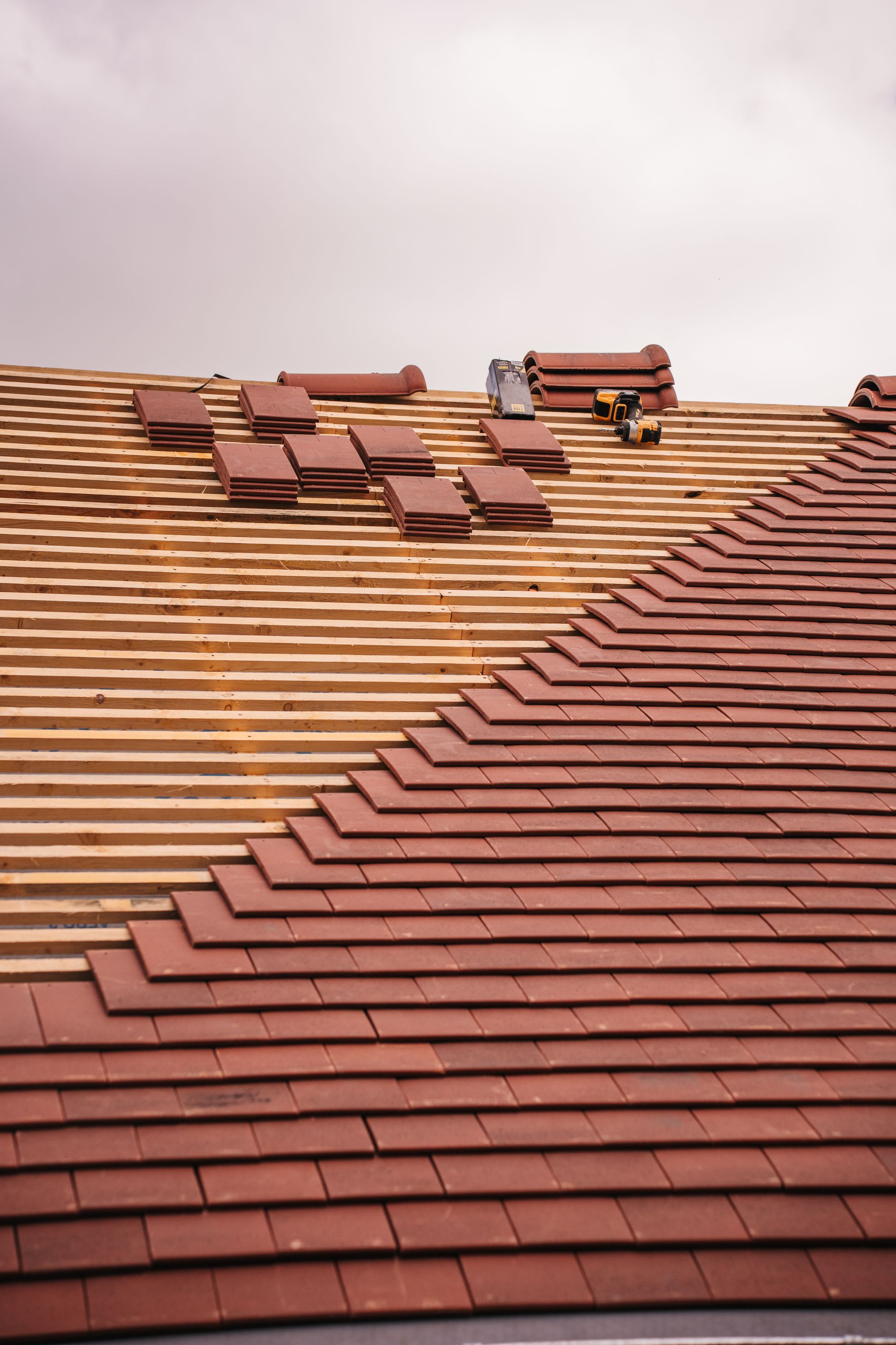 Tile roof mid-installation with battens and tools on the roof